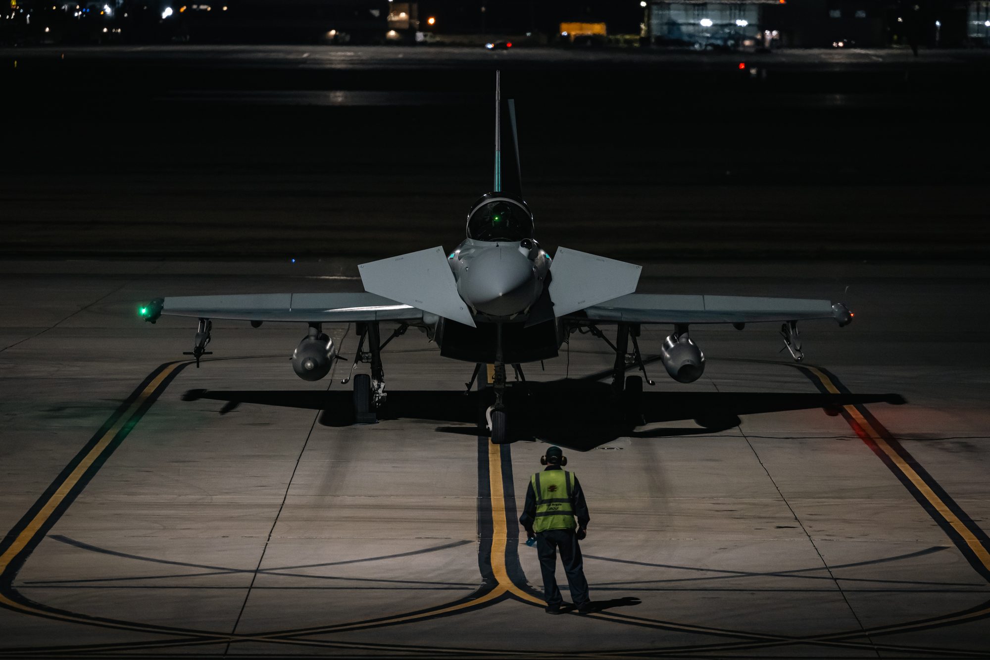 An RAF Typhoon with a ground crew member on the pan at night, Exercise Red Flag.